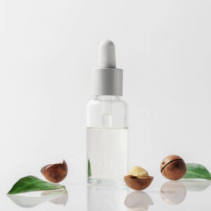 A bottle of macadamia nut oil on a grey background.