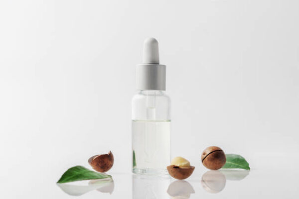 A bottle of macadamia nut oil on a grey background.