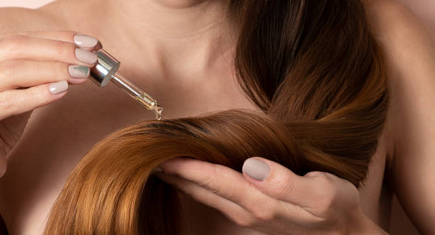 Woman applying hair serum closeup. cosmetic product