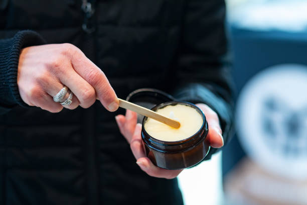 A woman's hands are seen sampling skin care balm.
