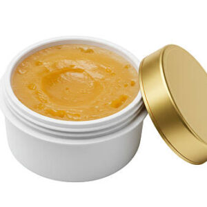 Isolated open jar of golden cosmetic cream or balm