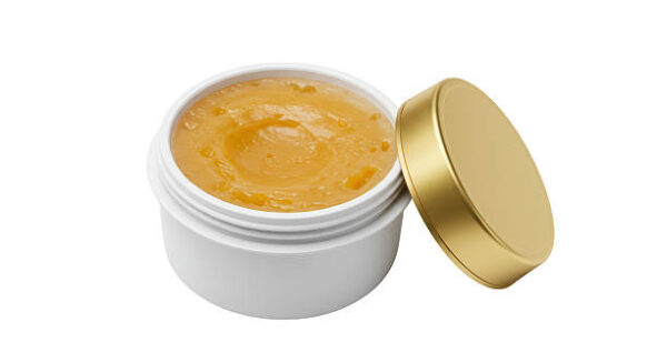 Isolated open jar of golden cosmetic cream or balm